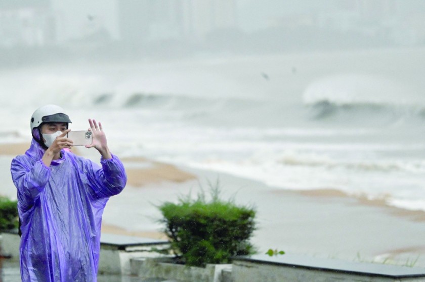 A resident records on their phone as waves crash onto Quy Nhon beach ahead of the arrival of Typhoon Kalmaegi in Gia Lai province in central Vietnam. - AFP