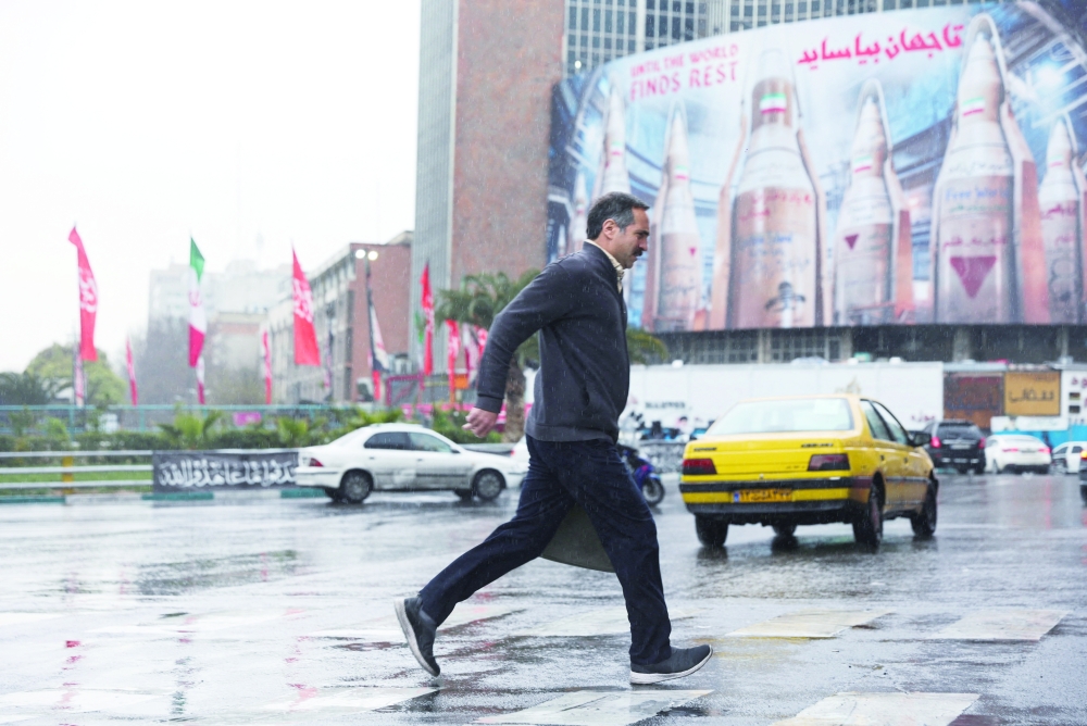 A man moves past a huge billboard displaying images of Iranian missiles, in Tehran. — Reuters