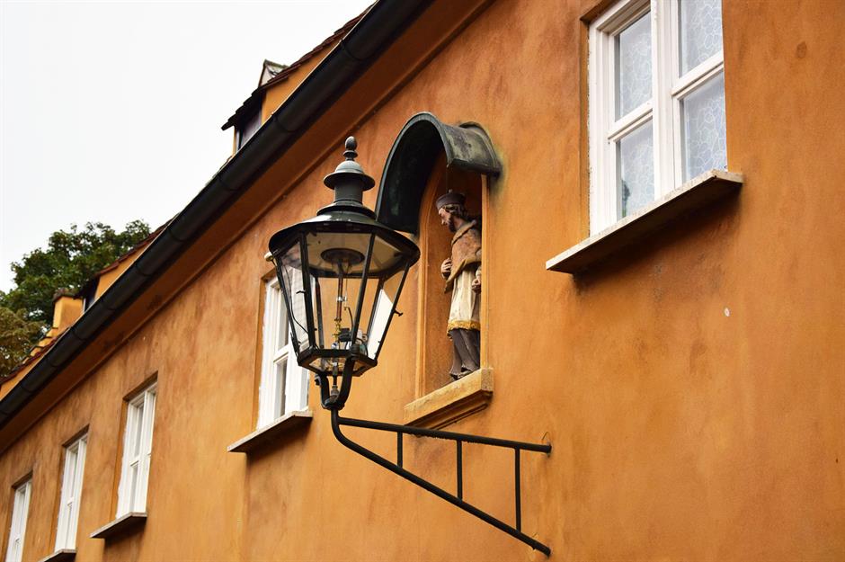 A gas lamp and a statue of a saint on the facade of the building. A gas lamp and a statue of a saint on the facade of the building.